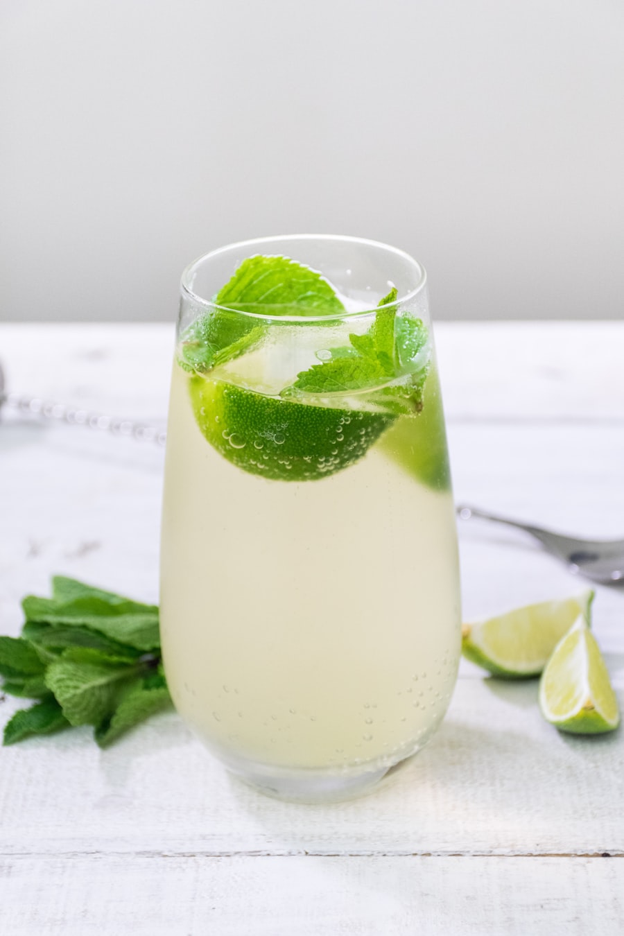 Loose green tea leaves and fresh botanical ingredients arranged on natural surface